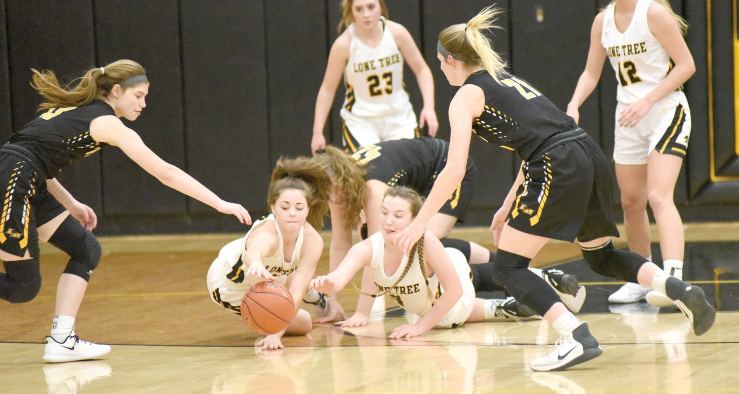 Lone Tree’s Holley Johnson (left) and Sara Branson dive for a loose ball in the Lady Lions’ 49-48 thrilling victory over Louisa-Muscatine.
